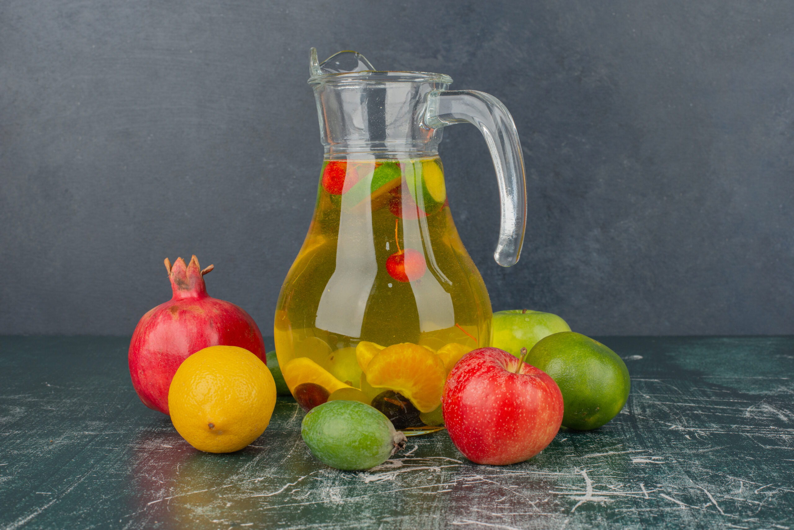 Mixed fresh fruits and glass of juice on marble table. High quality photo